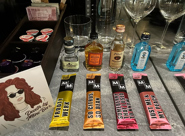 Miniature bottles of alcohol and Micmeco mixers on a bar counter.
