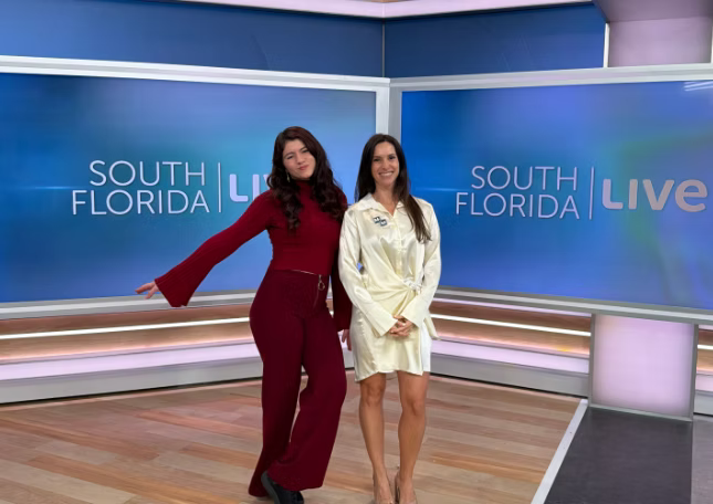 Two women standing in a South Florida Live studio with a blue and purple background.