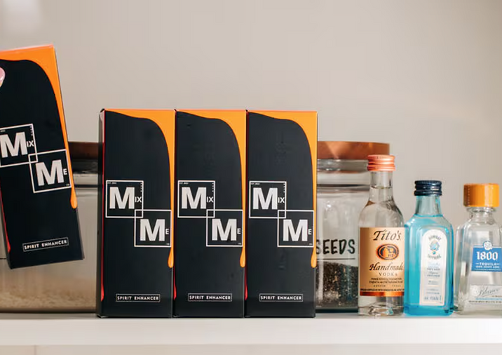 Four boxes labeled 'Mixmeco' on a shelf with bottles in the background